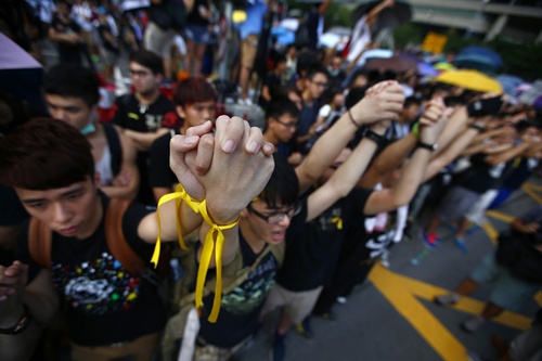 Những người biểu tình đòi dân chủ nắm tay khi tụ tập quanh Quảng trường Golden Bauhinia trong lễ thượng cờ mừng Quốc khánh Trung Quốc, đứng sau rào chắn của cảnh sát và chất vấn lãnh đạo Hong Kong, khi ông dự lễ thượng cờ nhân dịp Quốc khánh Trung Quốc. 