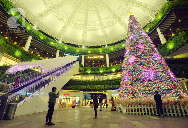 Nằm cạnh lối vào trung tâm thương mại Aeonmall Long Biên, cây thông Noel cao 15m được trang trí bằng dây thông, đèn Led, hoa sakura, những quả bóng nhựa nhiều màu, với tông màu chủ đạo là tím hồng huyền ảo.