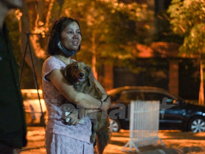 Một người phụ nữ mặt đen kịt vì ám khói của vụ cháy, chỉ kịp ôm theo chú chó cưng chạy nạn