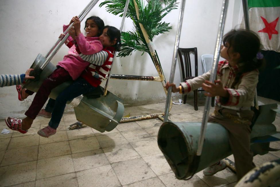 Các em bé gái chơi đùa trên ‘chiếc xích đu’ tạo từ vỏ tên lửa ở Damascus, Syria.