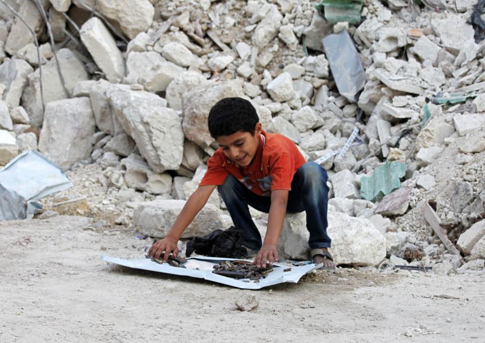 Ahmad, một cậu bé người Syria đang nghịch ngợm với bộ sưu tập các vỏ bom, đạn phía trước một ngôi nhà đổ nát tại quận Tariq al-Bab của Aleppo.