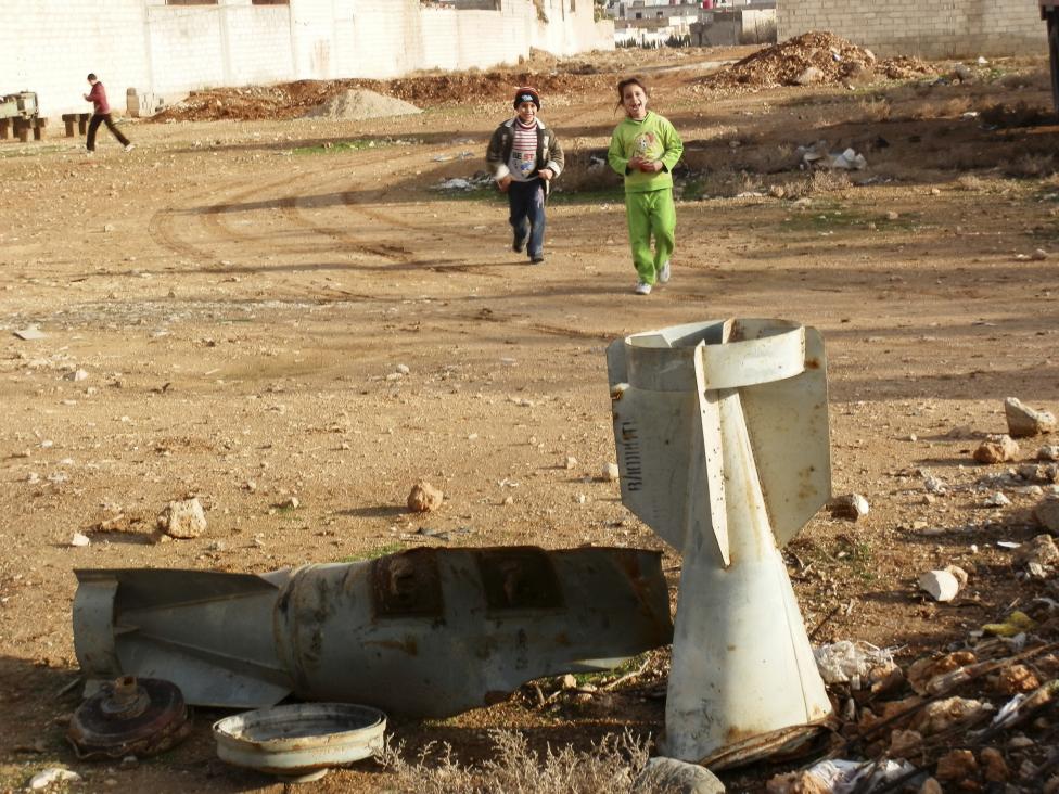 Trẻ em chơi gần các mảnh bom bị vỡ trong trận càn quét của các lực lượng không quân Syria.