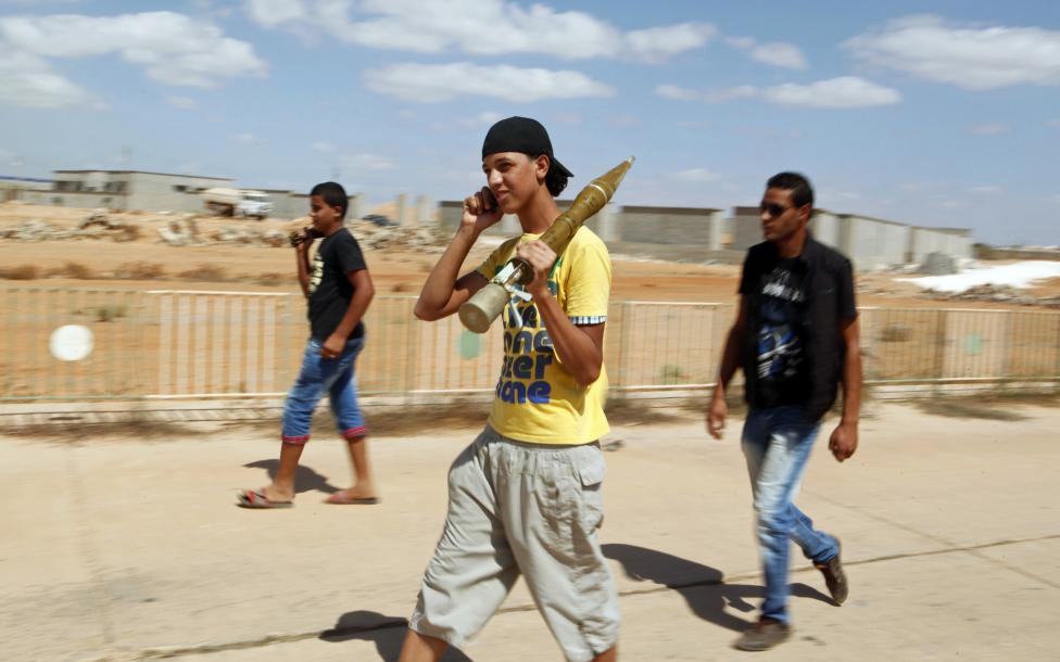 Một người thanh niên mang trên vai vỏ tên lửa và sử dùng điện thoại khi rời đi cùng lữ đoàn Rafalla al-Sihati, một bộ phận của quân đội Lybia.