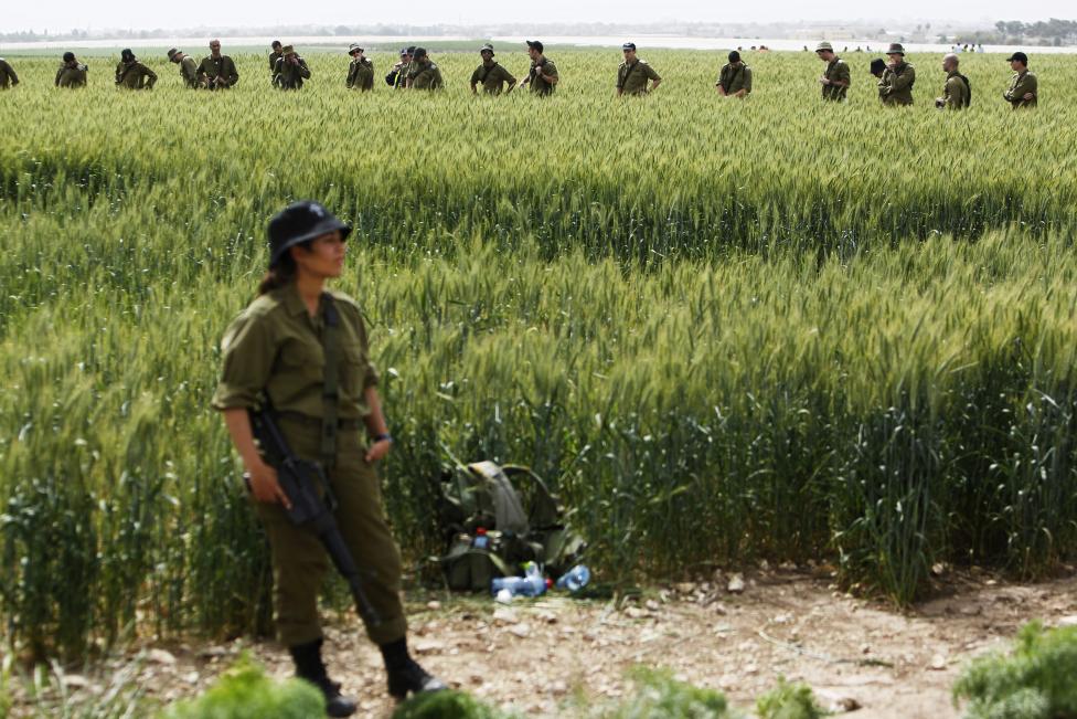 Một nữ binh sĩ đang canh gác để đồng đội của cô dò tìm mảnh vỡ máy bay tại cánh đồng Kibbutz Revadim, phía nam Israel. Nguồn ảnh: REUTERS/ Amir Cohen.