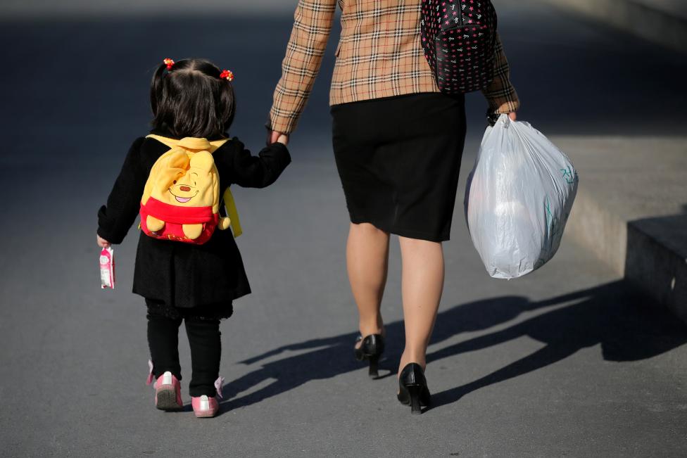  Một người phụ nữ đang dắt tay đứa trẻ đi trên con đường Các nhà khoa học Mirae (Mirae Scientists street) ở thủ đô Bình Nhưỡng