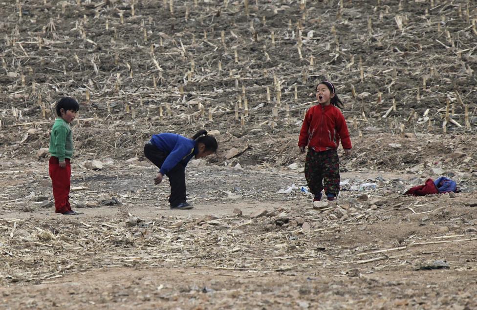 Những đứa trẻ Triều Tiên đang nô đùa trên bãi đất bên bờ sông Yalu, gần thị trấn Sinuiju (Triều Tiên) và đối diện với thành phố biên giới Dandong của Trung Quốc.