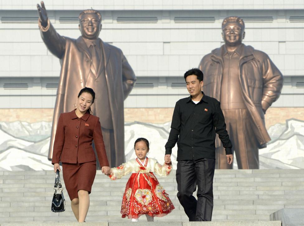 Một gia đình Triều Tiên đi bộ trước bức tượng đồng cựu lãnh đạo Triều Tiên Kim ll-Sung.