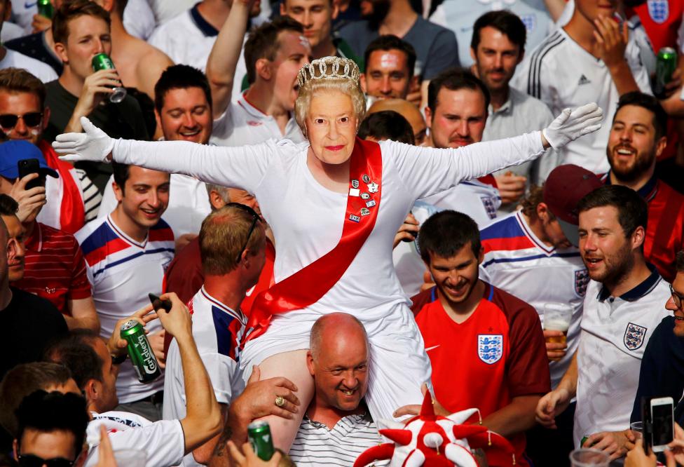 Một fan người Anh cổ vũ cho đội nhà bằng việc đeo chiếc mặt nạ mang hình nữ hoàng Elizabeth.