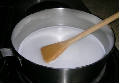 Đun nước cốt dừa + 100gr đường trên bếp lửa vừa, khuấy đều tay cho đến khi đường tan hết thì tắt bếp, để nguội. Bước này nên thực hiên trước khi ngưng ủ bột khoảng 1-2 tiếng cho nước cốt dừa kịp nguội.