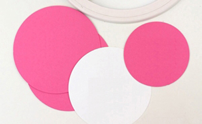 Cắt giấy màu hồng thành 2 hình tròn có đường kính 10cm làm đáy hộp và nắp hộp. Bạn cắt thêm 1 hình tròn đường kính 7,4cm làm các tép cam. Cắt giấy màu trắng thành 1 hình tròn đường kính 9,4cm.