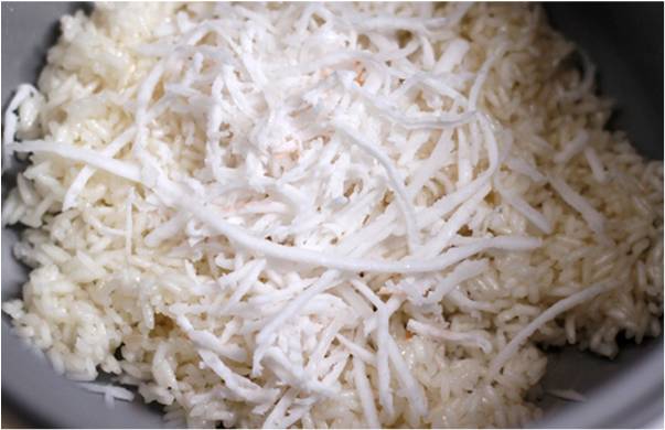 Trộn gạo với dừa, đảo đề, khi nước trong nồi hấp bắt đầu bốc hơi, đổ gạo vào, dàn đều bề mặt