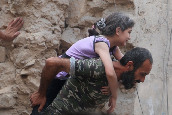 Một người đàn ông cứu một cô bé bị thương tại Aleppo. Ảnh: Reuters