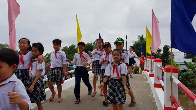 Nhiều em học sinh tiểu học hớn hở, vui hơn khi có cầu mới do hoa hậu Kim Nguyễn tài trợ. Ảnh: Thanh Niên 