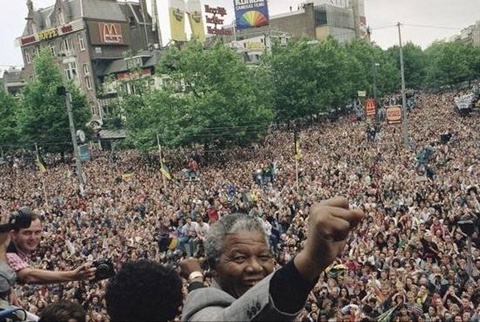 Sau khi ra tù, với tư cách lãnh đạo ANC ở Nam Phi, Nelson Mandela giơ nắm đấm sau khi phát biểu trước đám đông ủng hộ bao gồm khoảng 15.000 người, từ ban công nhà hát thành phố Amsterdam, Hà Lan hôm 16/6/1990. Ảnh: AP