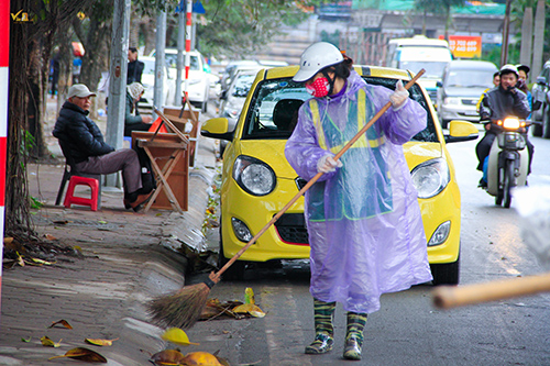 Những người lao công vệ sinh vẫn âm thầm quét đường, Gió làm rác bay nhiều nhưng chị vẫn chăm chỉ quét sạch.