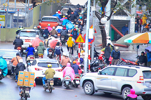 Từ sáng sớm, nhiệt độ Hà Nội giảm đột ngột khiến người đi đường phải khoác cả áo mưa chống cái lạnh 14 độ C.