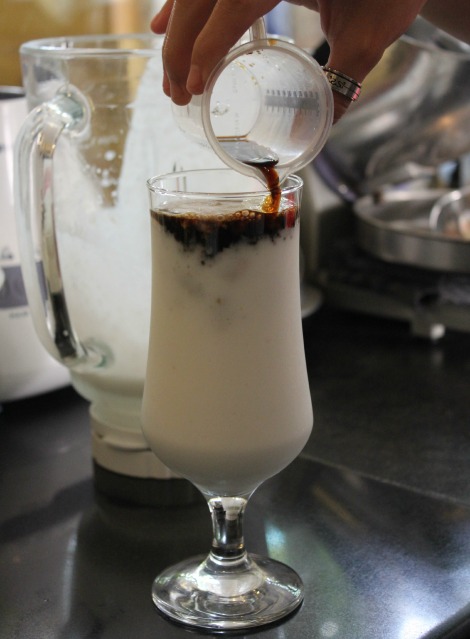 Sau khi xay xong sinh tố dừa, đổ từ từ cà phê vào ly sinh tố và khuấy đều