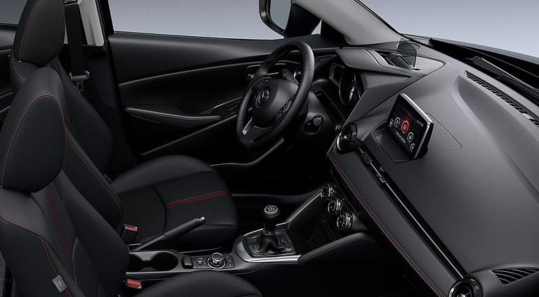 Nội thất của Mazda 2 sedan mang nét khỏe khoắn, thể thao. Ghế da khâu chỉ đỏ, viền táp-lô bọc da cũng được điểm xuyết bằng chỉ đỏ, một vài phần ốp táp-lô và mặt vô-lăng được làm bằng nhựa giả chất liệu carbon và đặc biệt là cửa gió điều hòa lấy cảm hứng từ động cơ máy bay giúp cho chiếc xe cỡ nhỏ có nội thất thực sự hấp dẫn. 