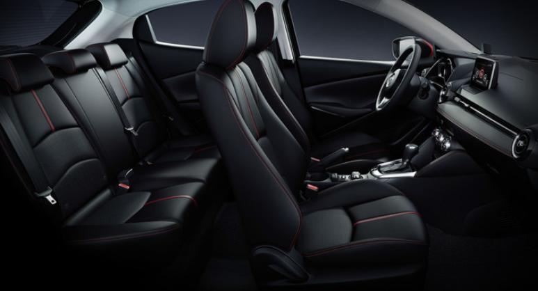 Nội thất của Mazda 2 sedan mang nét khỏe khoắn, thể thao. Ghế da khâu chỉ đỏ, viền táp-lô bọc da cũng được điểm xuyết bằng chỉ đỏ, một vài phần ốp táp-lô và mặt vô-lăng được làm bằng nhựa giả chất liệu carbon và đặc biệt là cửa gió điều hòa lấy cảm hứng từ động cơ máy bay giúp cho chiếc xe cỡ nhỏ có nội thất thực sự hấp dẫn. 