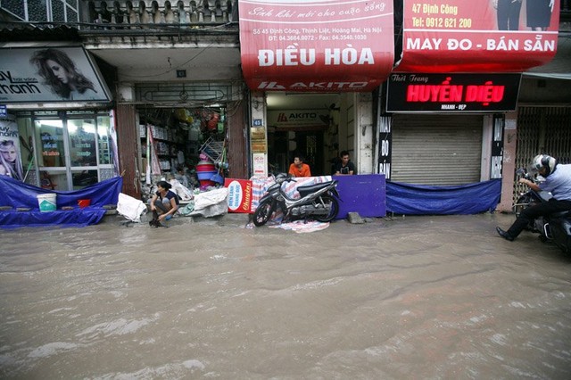 Mưa lớn khiến một số tuyến đường ở Định Công ngập úng cục bộ. Nhiều nhà dân phải làm bờ bao ngăn nước vào nhà. Ảnh Gia Đình và Xã Hội