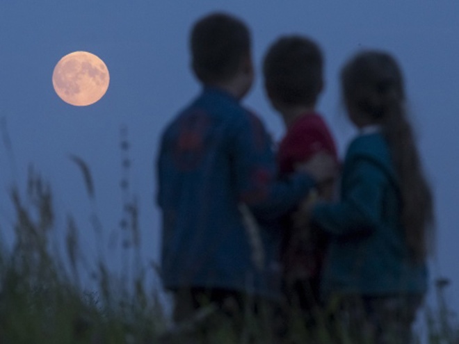 Trái với nhật thực, mọi người có thể ngắm nguyệt thực trực tiếp bằng mắt thường, càng khiến cho các đám đông càng đông hơn. Hình ảnh ba em bé đang ngắm trăng từ một khu định cư ở Ryazan, Nga. Ảnh: Reuters