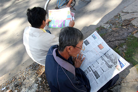 Những tờ báo được chia sẻ nhau cùng đọc bên vệ đường. Ảnh PLO