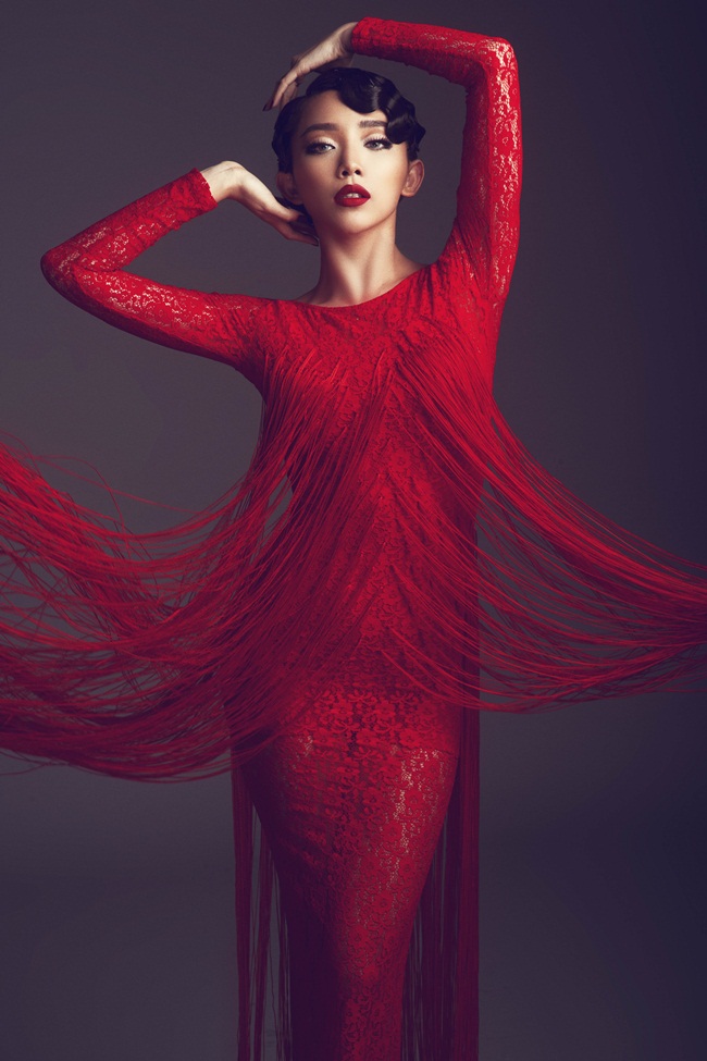 Cùng sử dụng sắc đỏ và chất liệu ren, lưới, thiết kế này lại là sự kết hợp hoàn hảo giữa váy ôm sát và áo choàng xẻ tay. Chi tiết rua rua hòa quyện vào trong những họa tiết ren to bản.