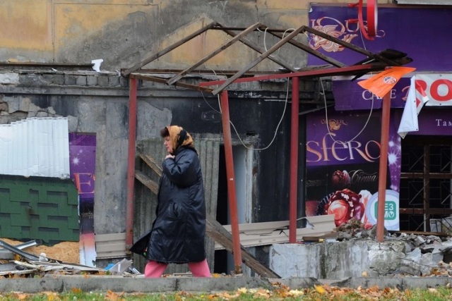 Người phụ nữ hối hả bước qua một tòa nhà bị phá hủy bởi bom đạn ở Donetsk, miền đông Ukraine