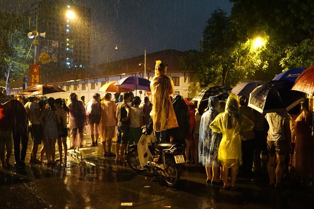 Người dân đội mưa tập trung theo dõi đoàn diễu hành. Ảnh Dân Trí