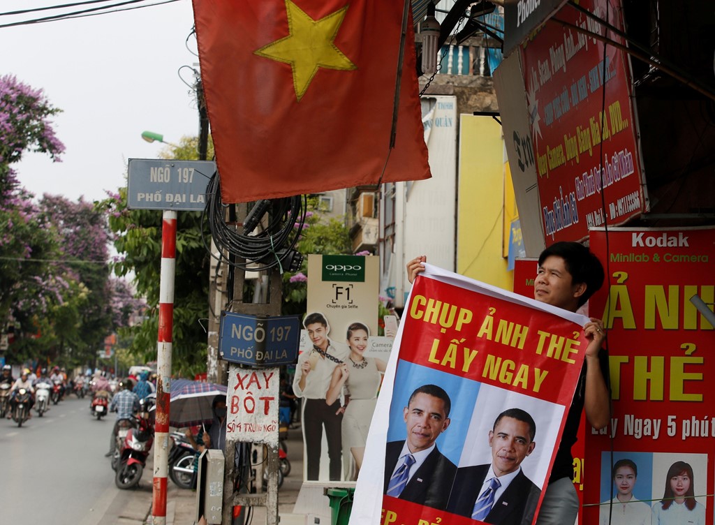 Một người đàn ông dùng hình ảnh của Tổng thống Obama để quảng bá cho cửa hiệu của mình tại Hà Nội. Ảnh: Reuters