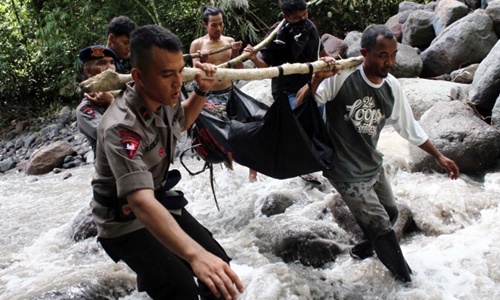Cảnh sát Indonesia và dân làng di chuyển thi thể của một nạn nhân bị nước cuốn trôi. Ảnh: AFP