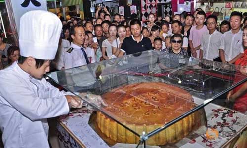 Thợ bánh đang cắt chiếc bánh trung thu có đường kính một mét thành những miếng nhỏ, trước khi mời khách miễn phí tại trung tâm mua sắm ở thành phố Vũ Hán, tỉnh Hồ Bắc, hôm 21/9/2013. Ảnh: Reuters.