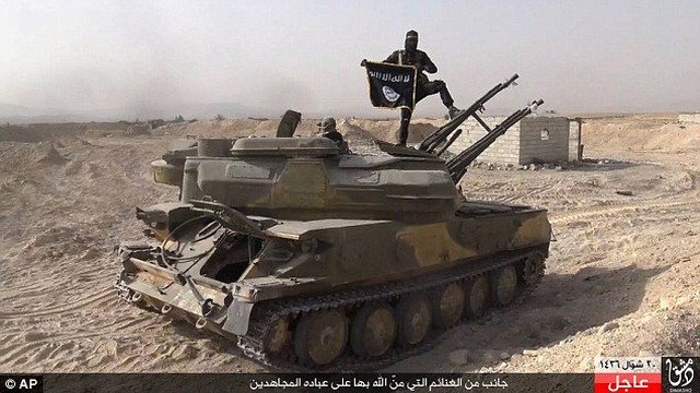 Một phiến quân cầm cờ của Nhà nước Hồi giáo (khủng bố IS) trên chiếc xe tăng mà chúng thu giữ được từ quân chính phủ Syria