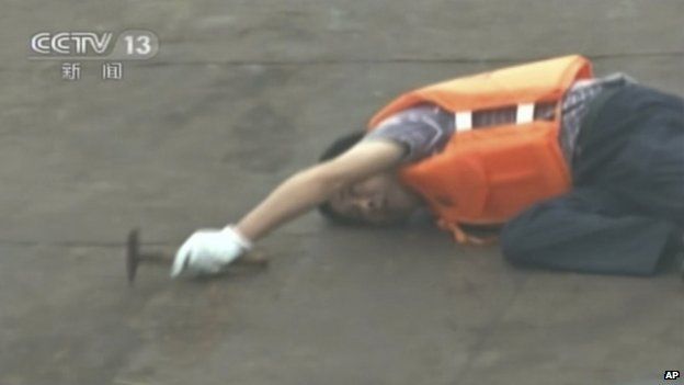 Một nhân viên cứu hộ lắng nghe xem có người còn sống trong tàu Trung Quốc bị chìm hay không