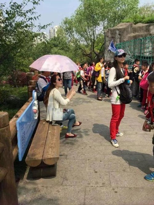 Ngay cả khi ngồi nghỉ, bên cạnh cô giáo người Trung Quốc này vẫn luôn có cậu học trò nhỏ cầm ô che nắng