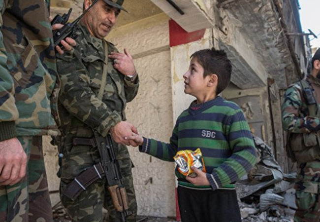 Một sĩ quan cao cấp quân đội Syria nói chuyện với em bé trong khu vực vừa giải phóng ở Aleppo, ttheo tình hình chiến sự Syria mới cập nhật 