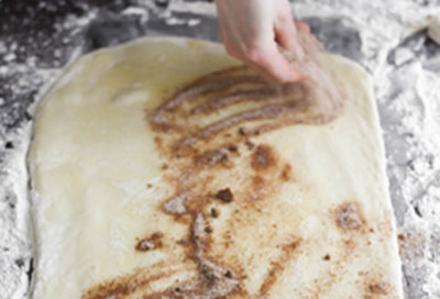 Phết 1 lớp bơ đun chảy lên bột bánh rồi rắc 1/2 phần bột quế, đường nâu và đường lên 1 phần bột bánh. Làm tương tự cho 1/2 phần bột bánh còn lại.