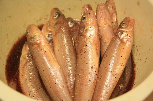 Rắc tiêu sọ và tiêu xay vào nồi cá rồi đổ hỗn hợp gia vị vào sao cho sâm sấp mặt cá, để 20 phút cho cá thấm gia vị.