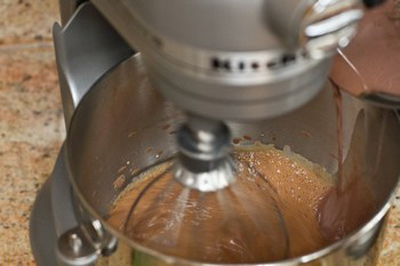 Từ từ cho hỗn hợp kem – bột ca cao vào trứng và tiếp tục đánh mạnh và liên tục.