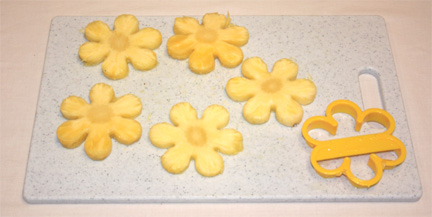 Dùng khuôn cắt hình bông hoa cắt từng miếng dứa tròn, tạo thành những bông hoa dứa 6 cánh.