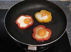 Đập trứng gà vào giữa khoanh ớt chuông. Đập cẩn thận không bị vỡ lòng đỏ nhé!