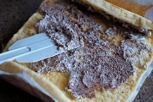 Bánh gato trải đều ra mặt phẳng, dùng dao hay thìa phết một nửa phần kem vừa đánh lên bề mặt rồi từ từ cuộn lại. 