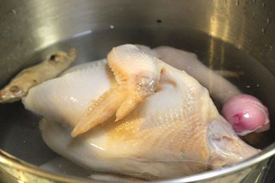 Gà rửa sạch, nhổ lại lông tơ cho thật sạch. Cho gà vào nồi, thêm gừng, hành khô nướng thơm và một thìa canh muối, đun sôi, thỉnh thoảng hớt bọt cho nước dùng được trong.