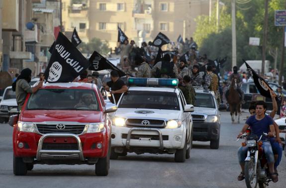 Các phần tử khủng bố IS vẫy cờ, tham gia một cuộc diễu hành quân sự dọc theo đường phố phía bắc tỉnh Raqqa của Syria hồi tháng 6