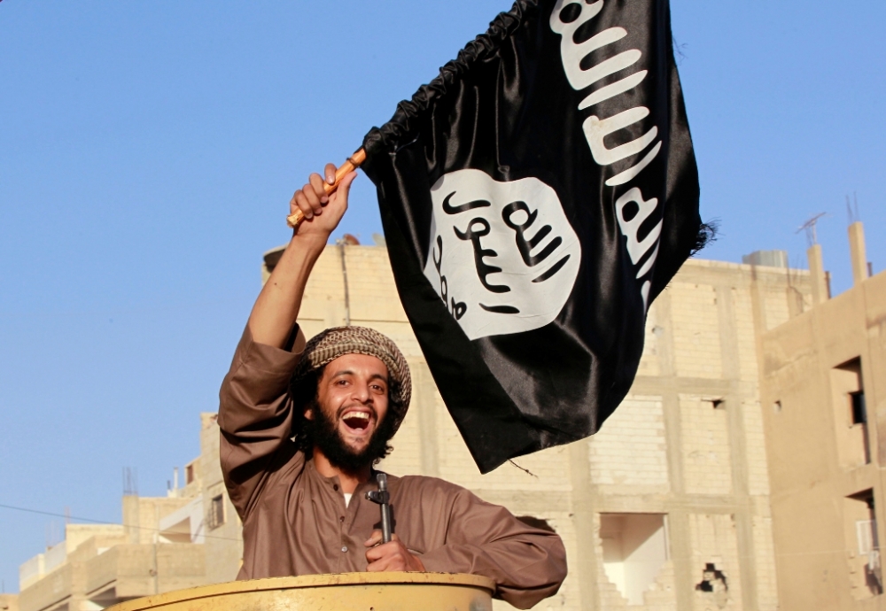 Một tay súng khủng bố IS giương cao lá cờ, tham gia một cuộc diễu hành trên đường phố Syria  