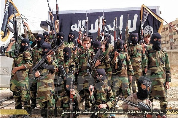 Những cậu bé trên dưới 10 tuổi mặc quân phục và cầm súng trường đứng trước lá cờ khét tiếng của khủng bố IS