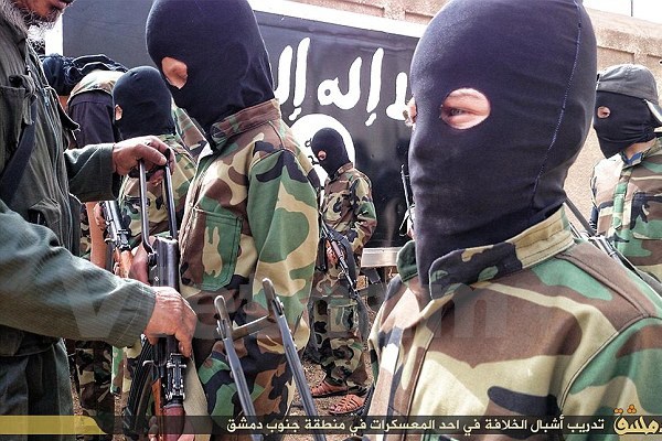 Một chỉ huy của khủng bố IS trao súng trường cho một cậu bé trong hàng ngũ