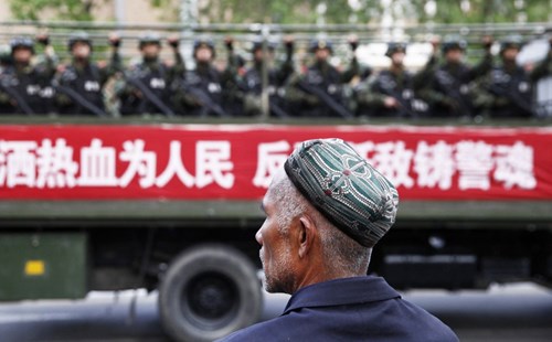 Một người đàn ông người Duy Ngô Nhĩ ở Tân Cương đang theo dõi hoạt động tuần tra chống khủng bố của chính quyền