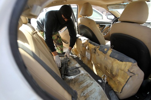 Nhân viên an ninh Iraq lôi khẩu súng máy giấu ở ghế sau một chiếc xe thu giữ ở Baghdad