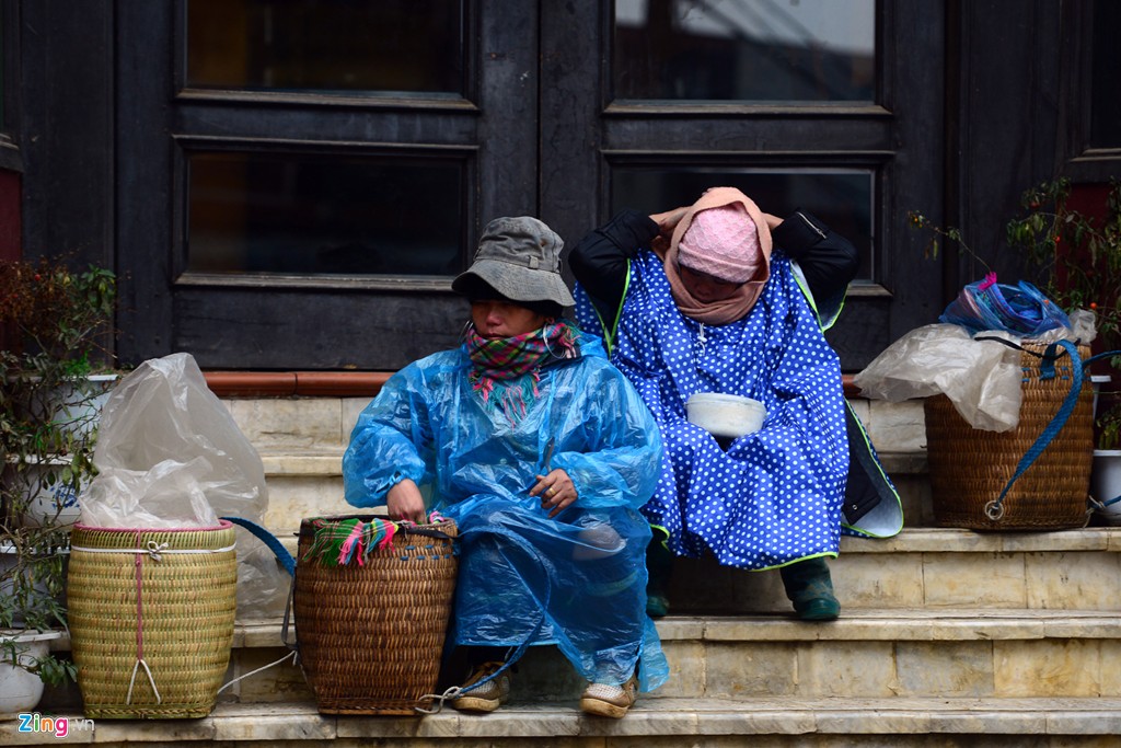 Hai phụ nữ người Mông co ro dưới hiên nhà dọc phố Cầu Mây buổi sáng sớm để mưu sinh, bán hàng cho khách du lịch.